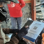 Salah satu pengunjung Wisata Gunung Kelud saat check in dengan scan QR Code PeduliLindungi yang sudah disediakan petugas.