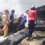 Petugas sedang memadamkan api di pabrik yang terbakar. foto: TRIWIYOGA/ BANGSAONLINE