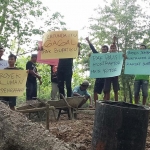 Warga Desa Bulak, Kecamatan Balong Ponorogo yang demo membentangkan poster yang bunyinya macam-macam, Sabtu (14/11/2020). foto: novian catur/ bangsaonline.com