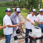 Dirut Petrokimia Gresik Dwi Satriyo Annurogo, dan Chairman MarkPlus Inc Hermawan Kartajaya secara bergantian mengisi pupuk dalam tabung ukuran sekitar 25 liter di mesin drone sebelum diterbangkan. foto: SYUHUD/ BANGSAONLINE