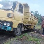 Sebuah truk terjebak dalam kubangan lumpur, sedangkan Kepala Desa Kesambi mengamati. foto: feri/ BANGSAONLINE