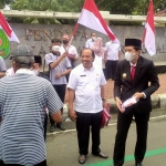 Wabup Trenggalek Syah Natanegara (baju hitam) saat membagikan bendera merah putih pada warga. Foto: HERMAN SUBAGYO/ BANGSAONLINE