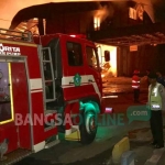 Petugas damkar berupaya memadamkan kobaran api yang terjadi di gudang PT Wonokoyo Jaya Corporindo di Desa Winong, Gempol, Ahad malam (7/4). foto: ANDY F/ BANGSAONLINE