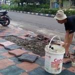 Warga yang khawatir memperbaiki sendiri trotoar yang rusak di depan rumah mereka.
