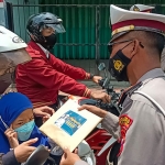 Petugas Satlantas Probolinggo Kota saat membagikan buku Yasin kepada pelanggar lalin.