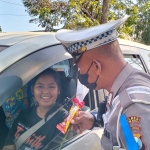 Petugas Polres Blitar Ktoa saat memberikan hadiah berupa bunga dan cokelat kepada pengendara yang tertib lalu lintas.