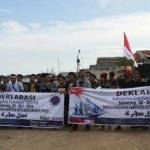 Puluhan pemuda dan mahasiswa Kepulauan Sumenep membentangkan spanduk pembentukan Kabupaten Kepulauan Sumenep, di Pelabuhan Kalianget, Minggu (8/5). foto: beritajatim.com