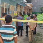 Rumah korban terpasang garis polisi. Terlihat sejumlah keluarga dan anggota kepolisian melakukan pemeriksaan. 