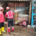 Tim Damkar Pemkab Gresik saat memadamkan toko sembako dan warkop yang terbakar. Foto: SYUHUD/ BANGSAONLINE.com
