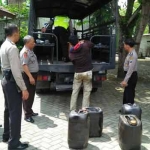 Polisi saat menurunkan barang bukti tujuh jerigen yang berisi minyak olahan dari truk untuk diamankan di Mapolres. foto: EKY NURHADI/ BANGSAONLINE