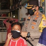 Kapolres Pasuruan AKBP Erick memasangkan masker ke seorang anak di Pasar Pandaan.