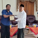 Dzulhilmi Bin Nawawi menyerahkan cindramata kepada Prof Dr KH Asep Saifuddin Challim, MA, di kediamannya Pondok Pesantren Amanatul Ummah Pacet Mojokerto, Selasa (10/9/2024). Foto: MMA/bangsaonline