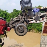 Separuh badan truk menggantung di atas Sungai Gunting.
