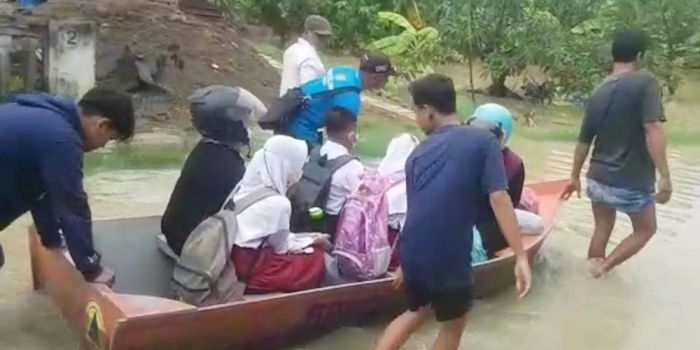 Warga di Kecamatan Balongpanggang saat mengantarkan siswa SD berangkat sekolah dengan perahu dampak desa terendam luapan Kali Lamong. foto: SYUHUD/ BANGSAONLINE