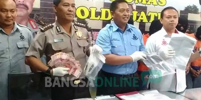 Petugas saat menunjukkan barang bukti berupa uang tunai. foto: sidharta/ BANGSAONLINE