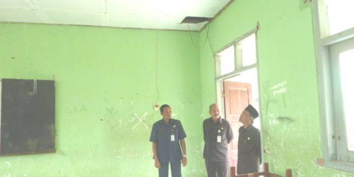 TERANCAM AMBRUK. Ketua Komisi C DPRD Gresik, Anwar Saddad BA melihat atap kelas di SMPN 1 Duduksampeyan yang jebol dan terancam ambruk. foto : much shopii/BangsaOnline.com