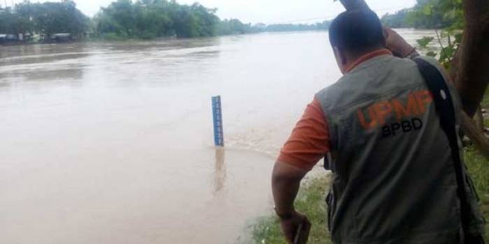 Hendro Wardono dari BPBD Jatim saat melihat ketinggian air di papan duga TBS. (foto: eky nurhadi/ BANGSAONLINE)