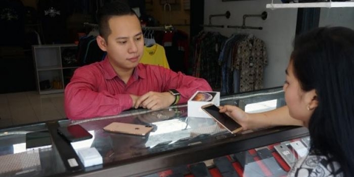 Sandy Dolorosa Hartono saat melayani pembeli di konter handphone miliknya. foto: RONY S/ BANGSAONLINE
