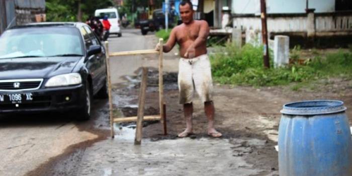 Salah satu warga Desa Sepande yang secara swadaya memperbaiki jalan rusak. (Khumaidi/BangsaOnline.com)