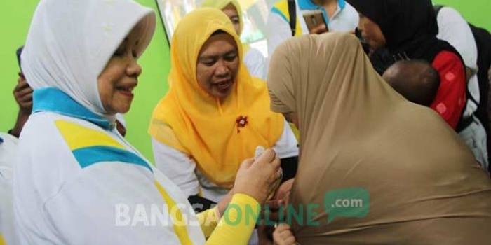Bupati Kediri dr. Hj. Haryanti Sutrisno saat memberikan imunisasi kepada balita yang hadir, dengan didampingi sang ibu di Balai Desa Kerkep Kecamatan Gurah Kabupaten Kediri.