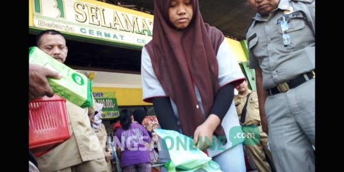 Penjaga minimarket membuang makanan yang tidak layak konsumsi atas permintaan petugas. foto: ROMZA/ BANGSAONLINE