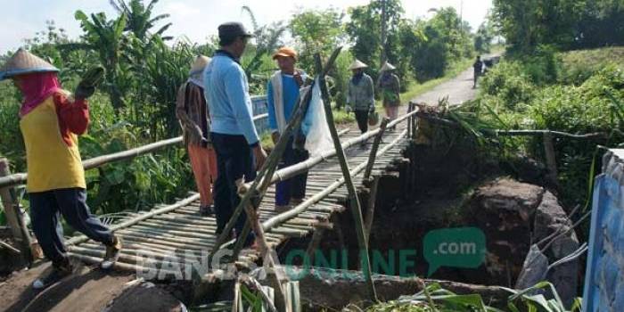 SEMENTARA: Warga gotong royong membuat jembatan alternatif dari bambu. foto: rony suhartomo/ BANGSAONLINE