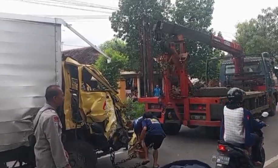 Truk boks yang ringsek diderek usai mengalami laka dengan truk pasir.