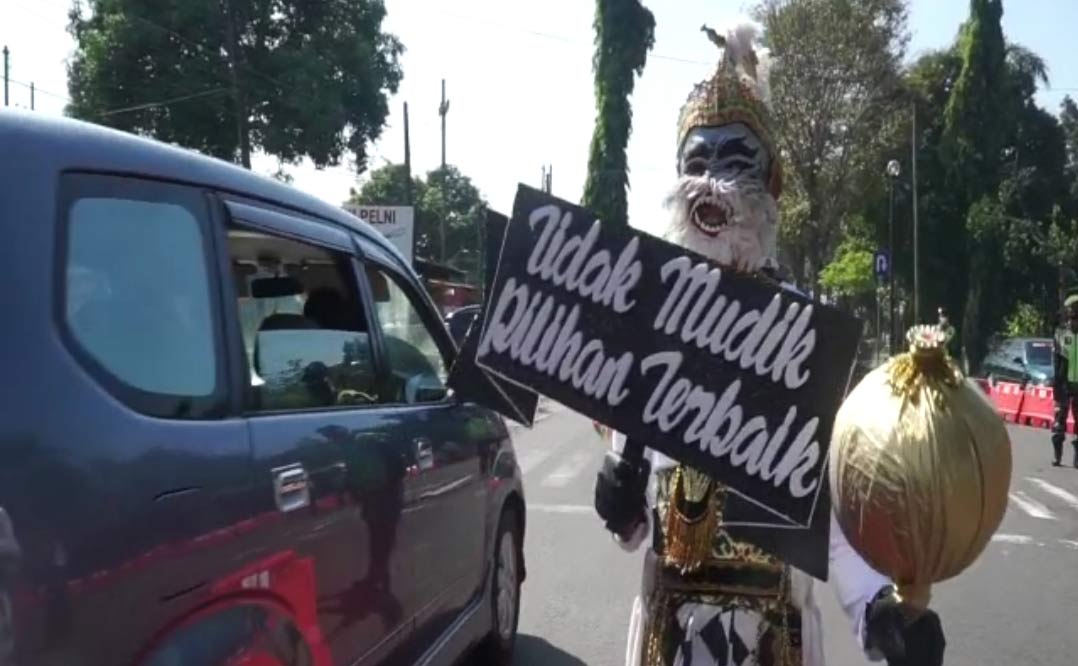 Sambil membawa poster imbauan, Hanoman memberikan sosialisasi kepada pengguna jalan untuk tidak mudik.