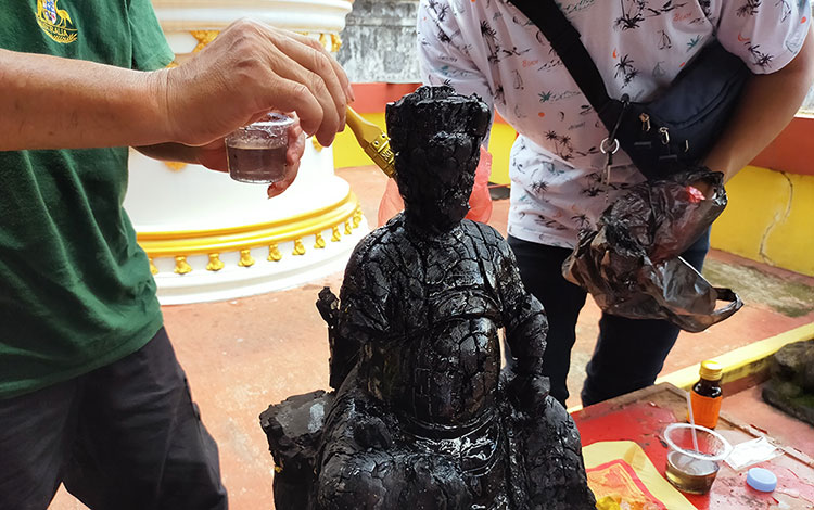Patung dewa yang sempat terbakar dilapisi resin dahulu sebelum dicuci.