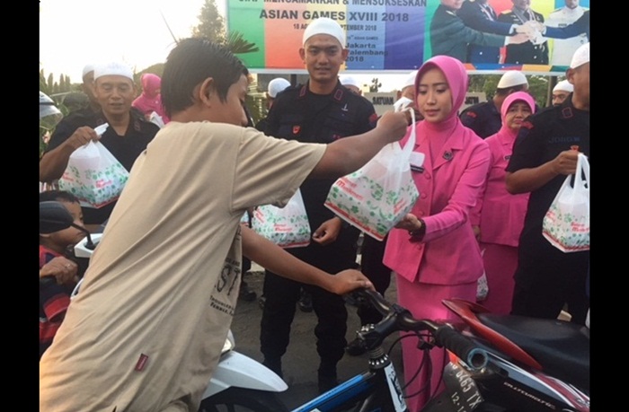 Kasubden 1 Den C Pelopor Satbrimob Polda Jatim Iptu Girindra Wardana Akbar Ramadhani bersama anggota saat bagi-bagi takjil bagi pengguna jalan. Foto: ARIF K/BANGSAONLINE

