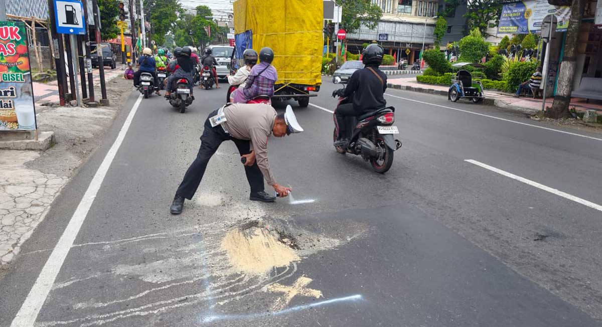 Petugas dari Satlantas Polres Blitar Kota saat memberikan penanda pada jalan rusak menggunakan cat semprot berwarna putih. 