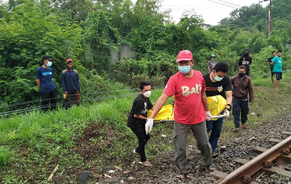 Petugas saat mengevakuasi Mr X yang tewas tersambar kereta api di depan bekas pabrik PT Soda Sidoarjo.
