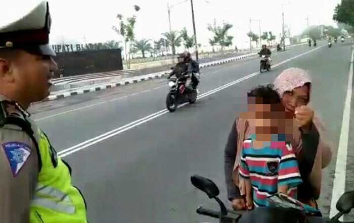 Seorang ibu dan anaknya dihentikan polisi karena tak memakai helm.