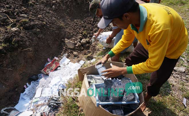 Petugas saat memasukkan ribuan petasan ke kubangan raksasa di TPA Gedangkeret. foto: RONY S/ BANGSAONLINE