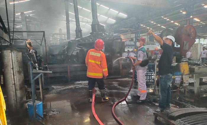 Tim Damkar Kabupaten Gresik memadamkan api yang membakar mesin produksi PT Indospring. Foto: SYUHUD/ BANGSAONLINE