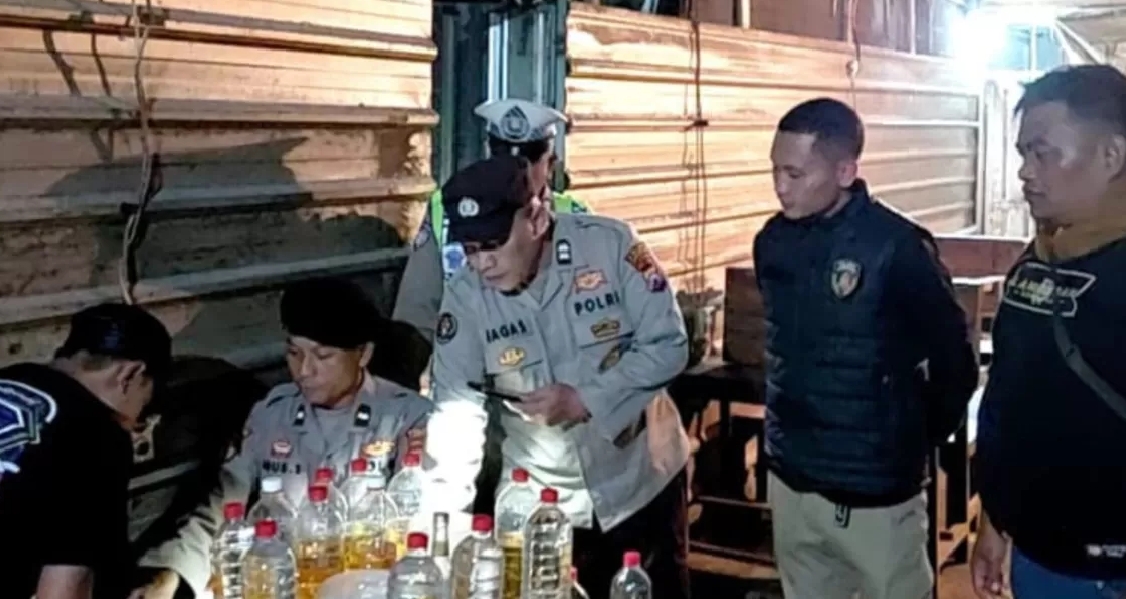 Anggota Polres Lamongan saat mengamankan barang bukti belasan botol miras jenis arak dari sebuah warung