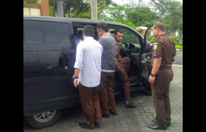 Petugas sedang memasukkan tersangka ke dalam mobil.