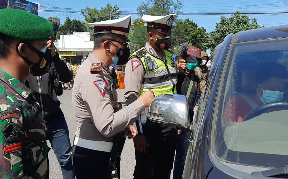 Petugas saat memberhentikan salah satu kendaraan di pos penyekatan Togokan Srengat, Blitar. 