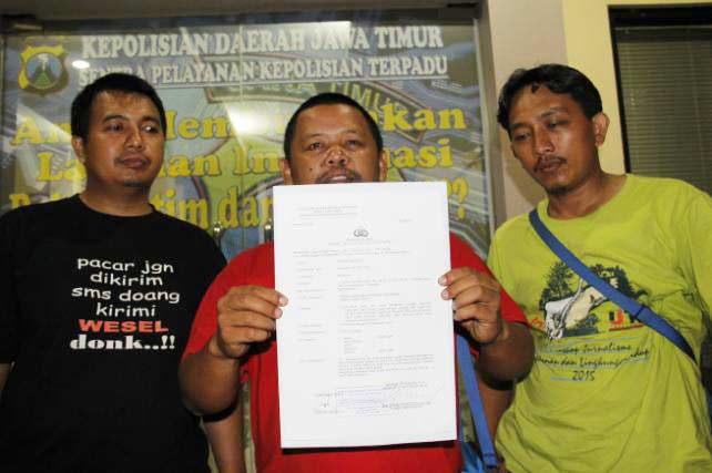 Wawan Sugiarto (tengah) wartawan TV One menunjukkan surat laporannya. foto: bruriy suarasurabaya