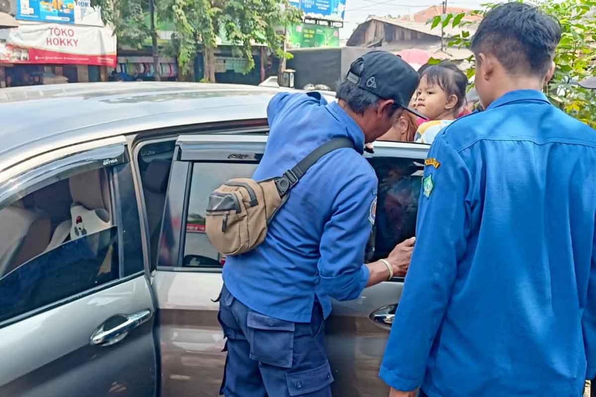 Petugas damkar unit Krian saat berupaya membuka jendela mobil. Foto: Ist.