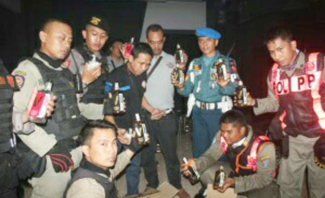 Petugas menunjukkan ratusan botol miras yang disita dari berbagai Cafe. foto: IRWAN S/ BANGSAONLINE