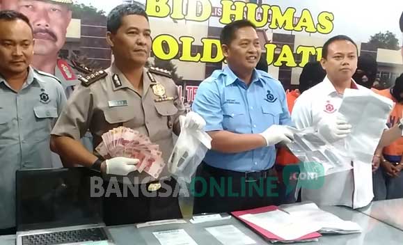 Petugas saat menunjukkan barang bukti berupa uang tunai. foto: sidharta/ BANGSAONLINE