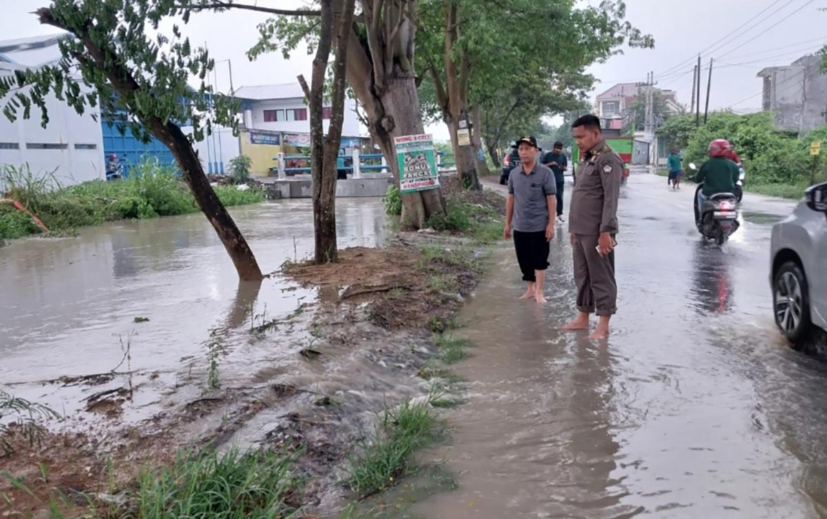 Camat Cerme Umar Hasyim mengecek air luapan Kali Lamong yang sudah meluber ke jalan raya. Foto: SYUHUD/ BANGSAONLINE