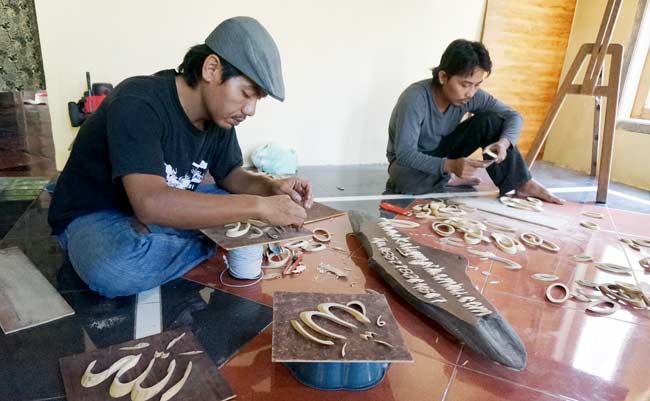 Mustamil saat menunjukkan cara pembuatan kaligrafi dari bambu. foto: RONY S/ BANGSAONLINE