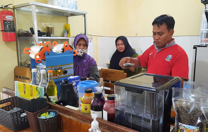 Seorang pegawai kafe inklusi di Tuban saat menata barang dagangannya.