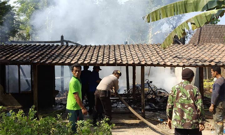 Petugas memadamkan kandang Sapi milik Saimun yang terbakar.
