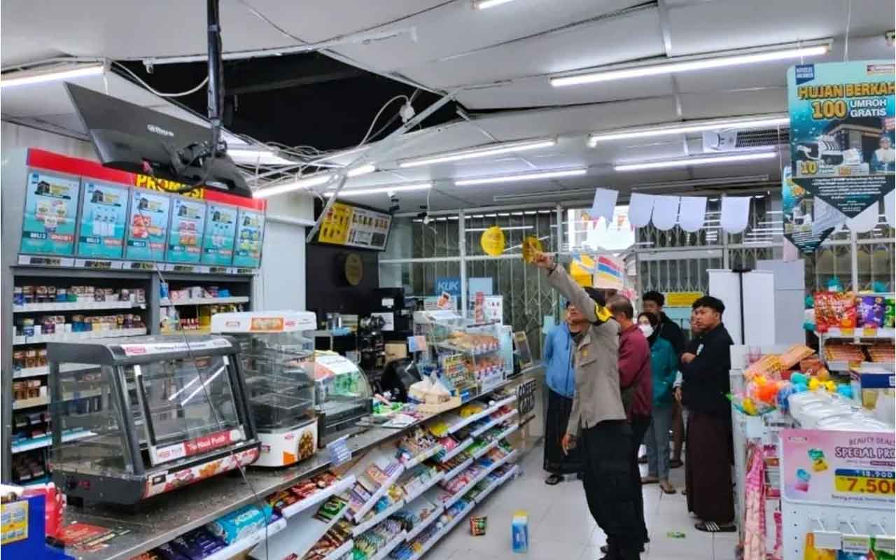 Petugas kepolisian saat menunjukkan atap jebol yang diduga menjadi tempat masuk para perampok di minimarket di Tulungagung. Foto: Humas Polres Tulungagung.