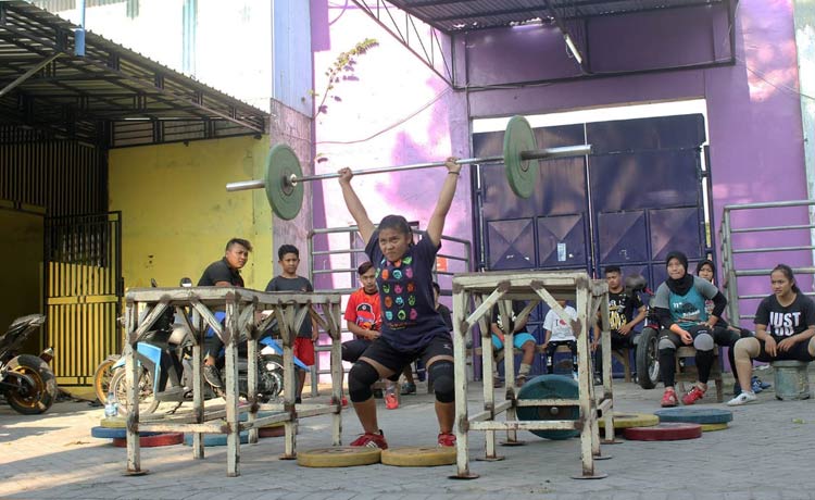 Salah satu atlet perempuan saat mencoba angkat beban disaksikan para atlet lainnya.