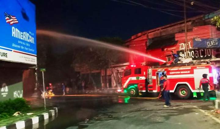 Para petugas Damkar sedang menyemprotkan air ke toko springbed.