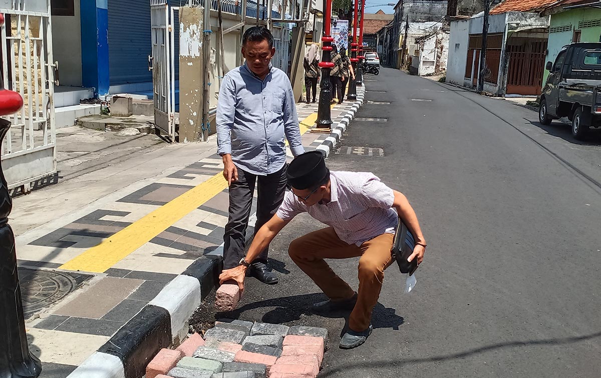 Ketua Komisi III DPRD Gresik Sulisno Irbansyah bersama Sekretaris Abdullah Hamdi menutup saluran yang penutupnya hilang dengan batu bata. Foto: SYUHUD/ BANGSAONLINE